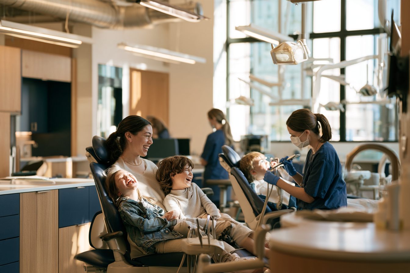 A mom and her two kids having cleanings in side-by-side chairs